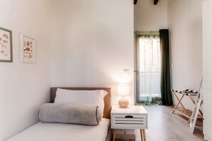 A bedroom with a bed, bedside table with a lamp, a window with curtains, and a drying rack. - Near the lake and the center (FLORIDA ASCONA Room 20) (Ascona)