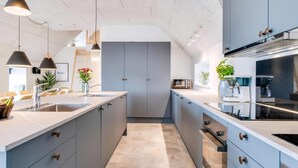 A modern kitchen with grey cabinets, a large island, stainless steel appliances, and pendant lighting. - VillaVilla 528 - Søndervig, Vestjylland (Ringkøbing)