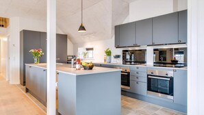 A modern kitchen with grey cabinetry, a central island, stainless steel appliances, and a pendant light. - VillaVilla 528 - Søndervig, Vestjylland (Ringkøbing)