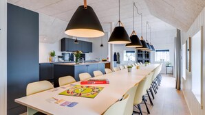 A modern kitchen with dark cabinets, a central island, and pendant lighting. - VillaVilla 528 - Søndervig, Vestjylland (Ringkøbing)