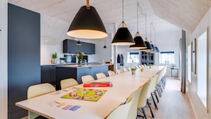 A modern kitchen with dark cabinets, a central island, and pendant lighting. - VillaVilla 528 - Søndervig, Vestjylland (Ringkøbing)