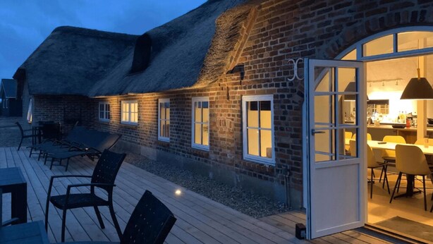 A thatched-roof building with a wooden deck and outdoor seating. - VillaVilla 528 - Søndervig, Vestjylland (Ringkøbing)