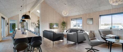 A modern office space with a long conference table, black leather sofas, and a large window with a view of parked cars.