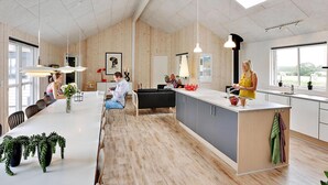 A modern kitchen with wooden flooring, a central island, pendant lighting, and a large window providing natural light. - VillaVilla 318 - Skåstrup Strand, Fyn og øer (Bogense)