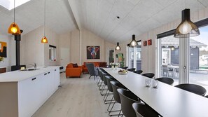 A modern kitchen with a long island, black chairs, and pendant lighting.