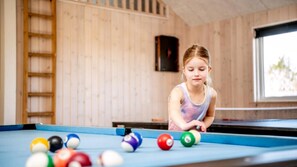 A pool table with balls, a wooden wall, and a window.