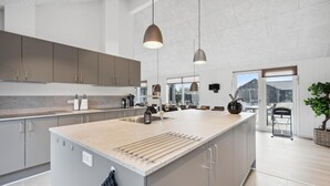 Eine moderne Küche mit einer großen Kochinsel, Edelstahlgeräten und Pendelleuchten.