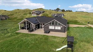 Een modern huis met een overdekte patio, een nummer 30-bord en een kleine glijbaan in een gazon.