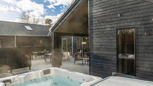 Un espace bien-être comprenant un jacuzzi et des sièges à l’extérieur.