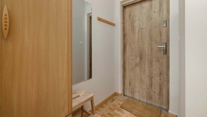 Una porta in legno con una maniglia di metallo, un piccolo sgabello di legno e uno specchio appeso al muro.