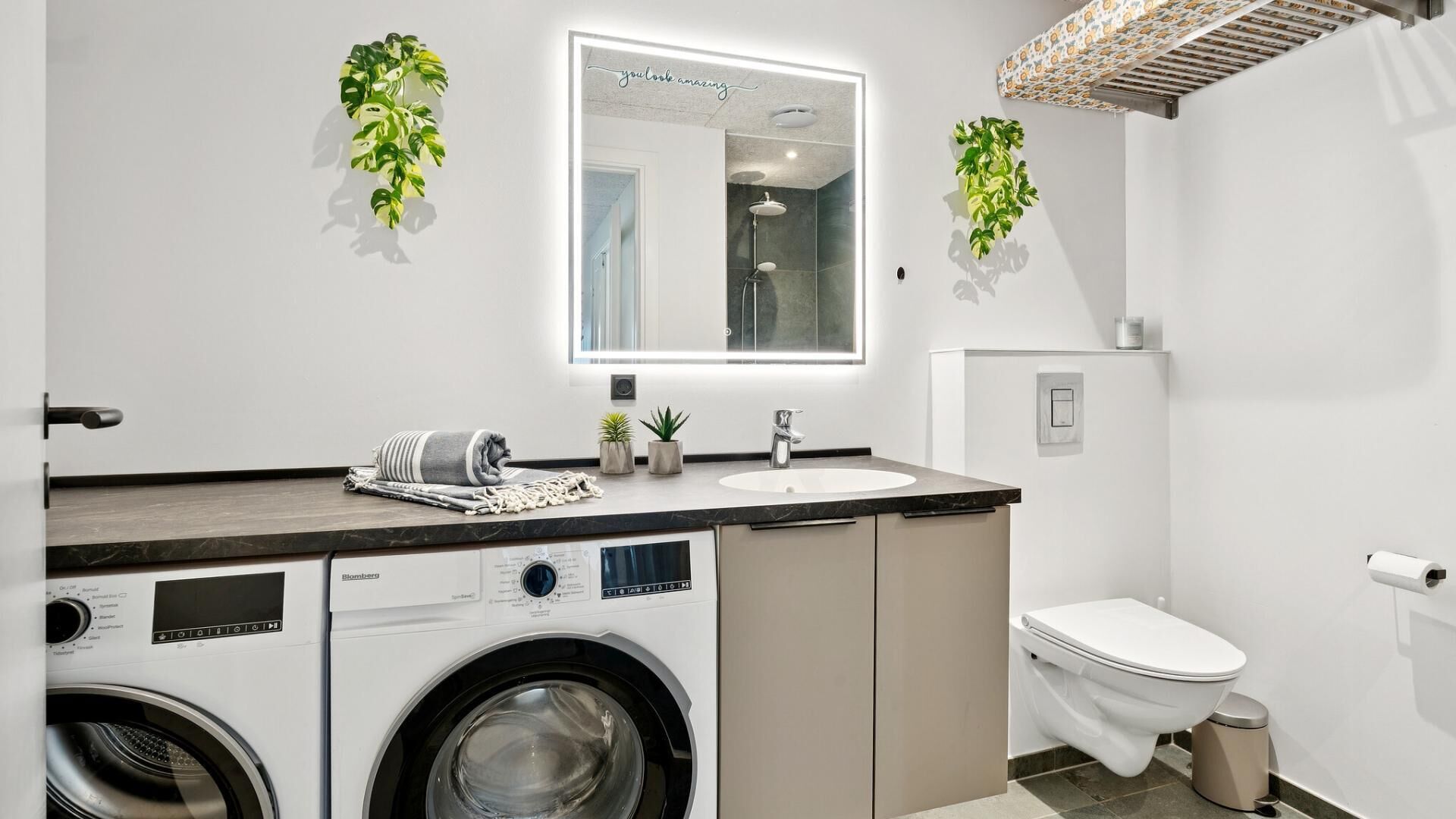 Een moderne badkamer met een wasmachine, een wastafel en een toilet.