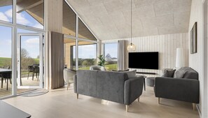 A spacious living room with a large TV, grey sofas, and a view of the outdoors. - VillaVilla 906 - Skåstrup Strand, Fyn og øer (Bogense)