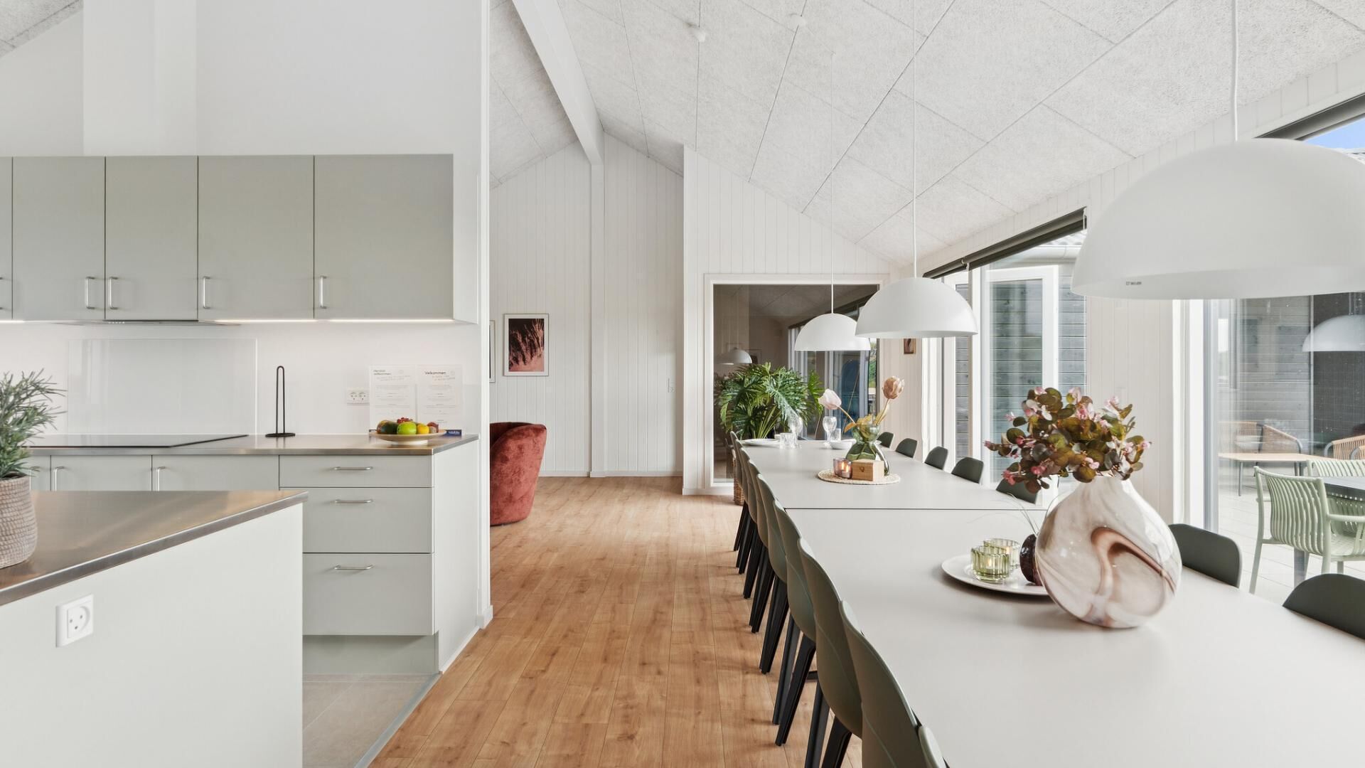 A modern kitchen with white cabinets, a wooden countertop, and a dining area with a long table and chairs.