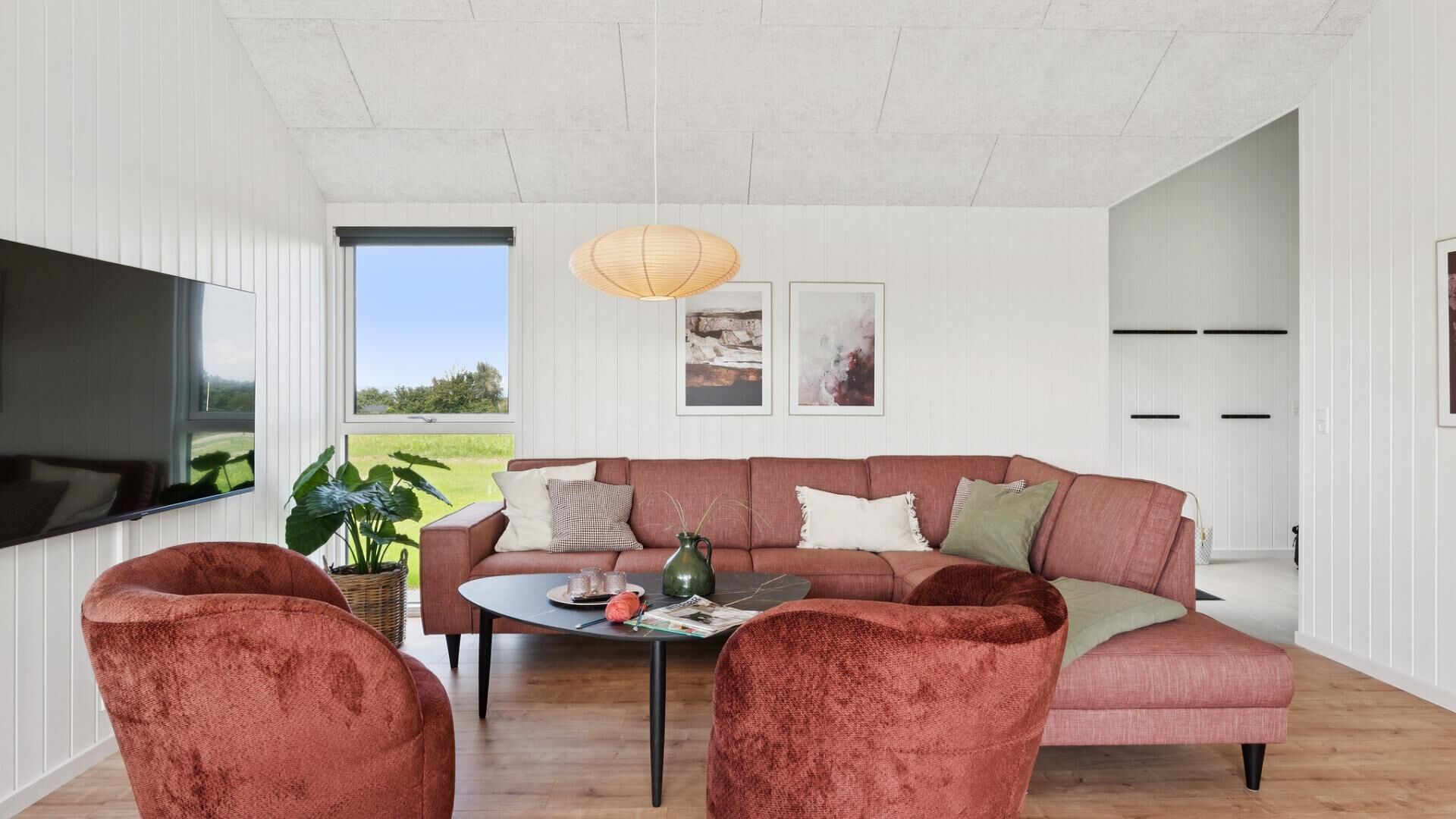 Un salon moderne avec un grand canapé d’angle, une table basse et un téléviseur à écran plat.