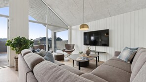 Un salon moderne avec un grand canapé, une table basse et un téléviseur fixé au mur.
