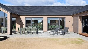 A modern building with a patio area featuring outdoor seating and a covered section. - VillaVilla 901 - Skåstrup Strand, Fyn og øer (Bogense)
