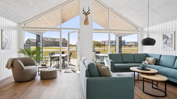 Un salón espacioso con un gran ventanal que da a un patio exterior, una cabeza de animal montada en la pared y una decoración de estilo moderno.