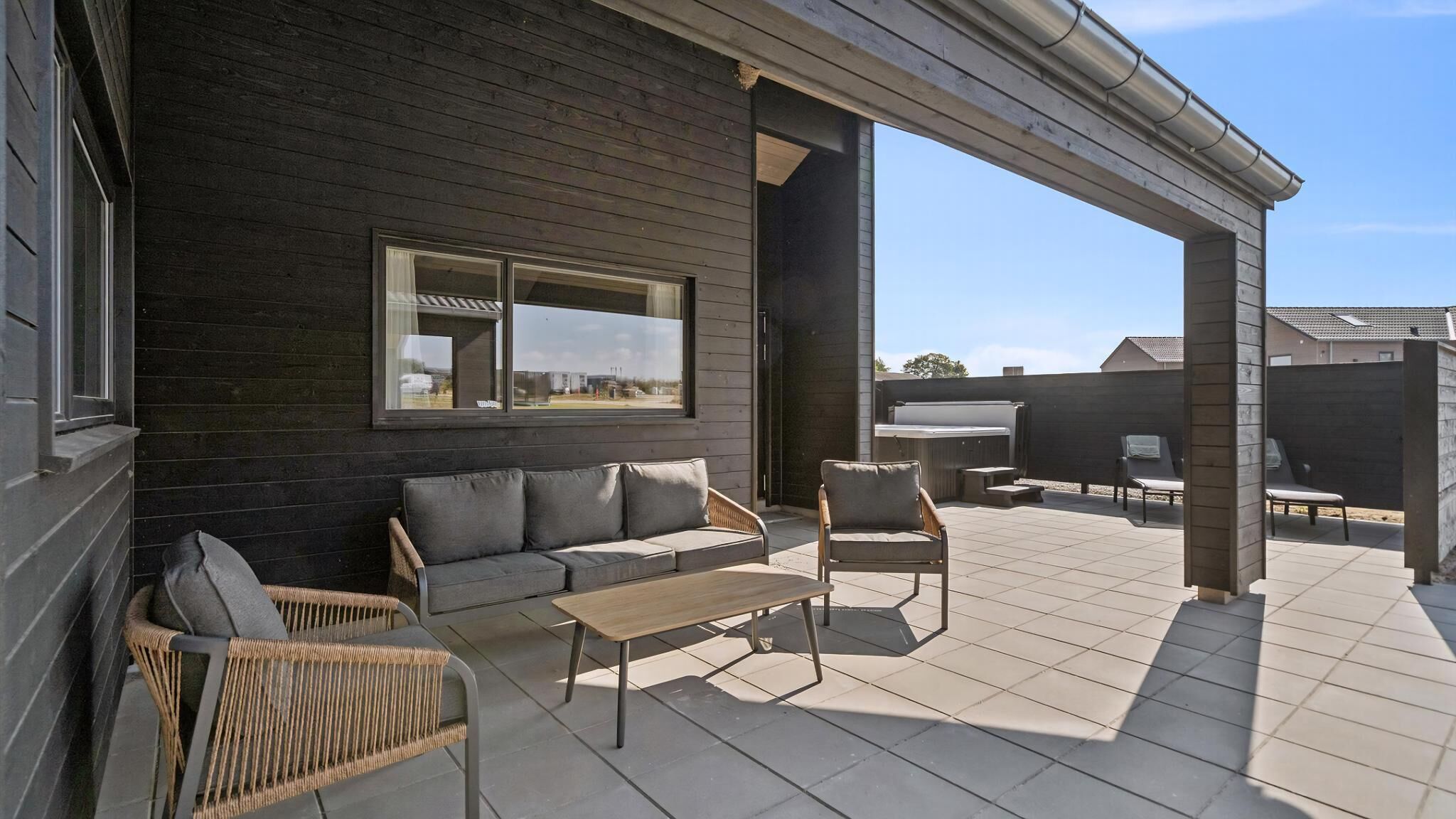 Eine Terrasse mit einer Couch, Stühlen und einem Tisch.