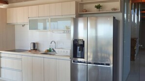 A modern kitchen with white cabinets, a stainless steel refrigerator, and a wooden ceiling. - HOP Aloha Beachfront House With Direct Access (Chincha Baja)
