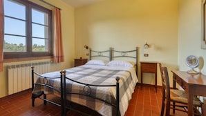 A bedroom with a metal bed frame, a wooden nightstand, a chair, and a desk with a mirror. - Agriturismo Polgara - Apt 2 - two bedrooms (Casciana Terme Lari)