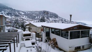 A snow-covered residential area with a modern house featuring large windows, a balcony, and a chimney. - Goura Guesthouse Mountain Twin Suite Lake Doxa (Sikyona)