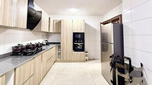 Une cuisine moderne avec des meubles de couleur bois clair, un réfrigérateur en acier inoxydable et un four encastré.
