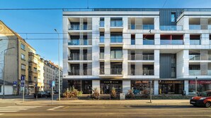A modern multi-story building with a ground-floor retail space, including a wine shop and a kebab restaurant. - Spacious Apartment | 2 Bedrooms | Underground Parking (Poznań)