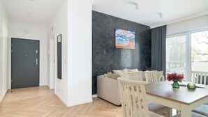A modern living room with a sofa, dining table, and chairs. - Spacious Apartment | 2 Bedrooms | Underground Parking (Poznań)