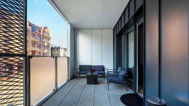 A modern balcony with a sofa, a small table, and a trash bin. - Spacious Apartment | 2 Bedrooms | Underground Parking (Poznań)