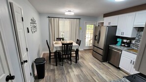Une cuisine compacte avec un coin repas, comprenant un réfrigérateur, une cuisinière et des placards.