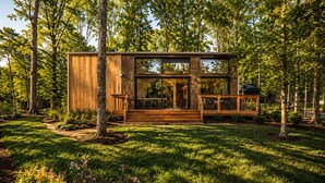 A modern wooden cabin with large windows, a deck, and a surrounding forest. - Wabi Sabi at The Retreat at Water's Edge (Tracy City)