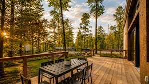 An outdoor deck with a table and chairs, surrounded by trees and a building. - Wabi Sabi at The Retreat at Water's Edge (Tracy City)