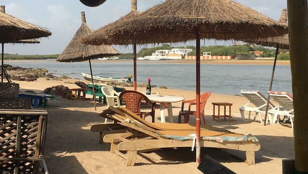 A beach with thatched umbrellas, lounge chairs, and a table with chairs. - CHARMING VILLA in SOMONE Private Pool, Beautiful Garden! Lagoon & Mangrove (Somone)