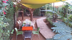 An outdoor patio area with a table and chairs, surrounded by greenery and a stone pathway. - CHARMING VILLA in SOMONE Private Pool, Beautiful Garden! Lagoon & Mangrove (Somone)
