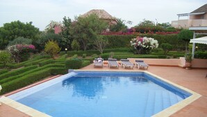A rectangular swimming pool with a tiled edge, surrounded by a brick patio. There are three lounge chairs with striped cushions aligned along the pool's edge. - CHARMING VILLA in SOMONE Private Pool, Beautiful Garden! Lagoon & Mangrove (Somone)
