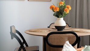A dining area with a round table, chairs, a vase with flowers, and framed artwork on the wall. - RentPlanet - przy Dworcu Centralnym (Warsaw)