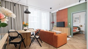 A modern living room with a wooden dining table, two chairs, a sofa, and a TV. - RentPlanet - przy Dworcu Centralnym (Warsaw)