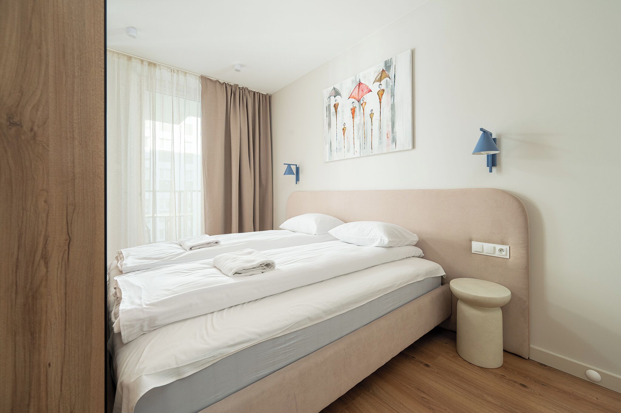 Una camera da letto con un letto, un comodino, una lampada a parete e un quadro.