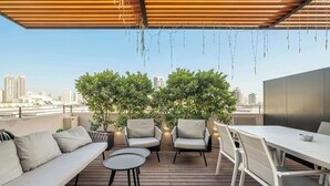 Une terrasse sur le toit avec une plateforme en bois, des sièges d’extérieur et une vue panoramique sur la ville.