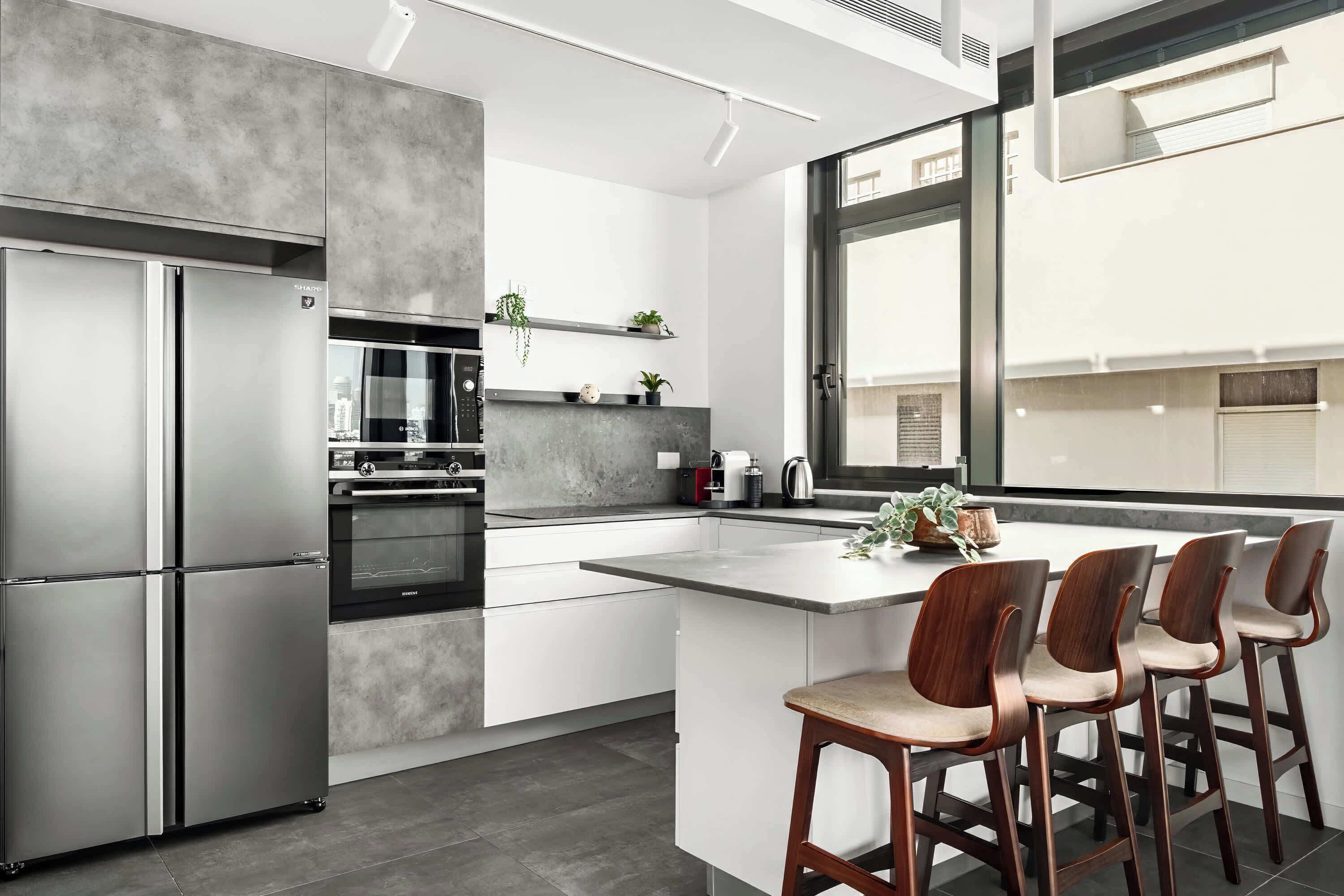 A modern kitchen with a large island, stainless steel appliances, and a view of the city.