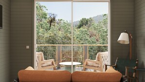 A room with a large window, two chairs, a small table, and a lamp. - Outbound Yosemite (Oakhurst)