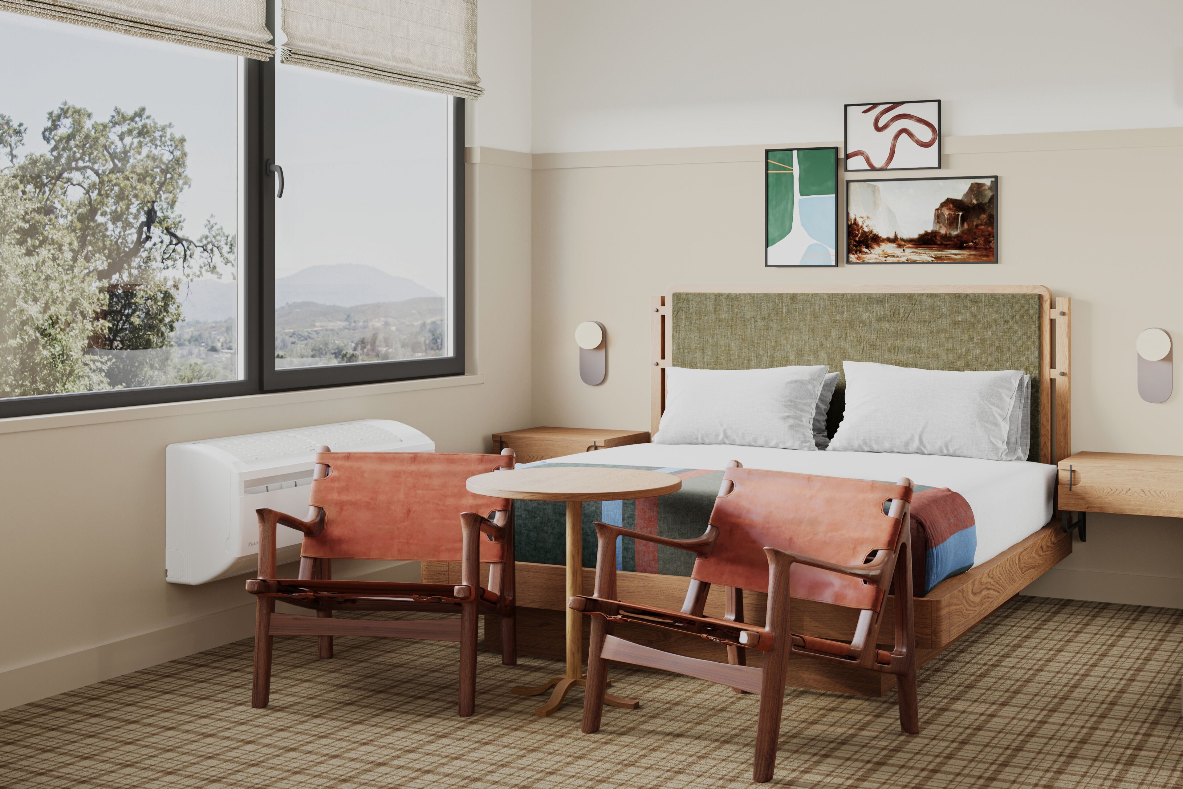 Une chambre d’hôtel avec un lit, deux chaises, une petite table, une fenêtre donnant sur des arbres et des montagnes, et des œuvres d’art accrochées au mur.