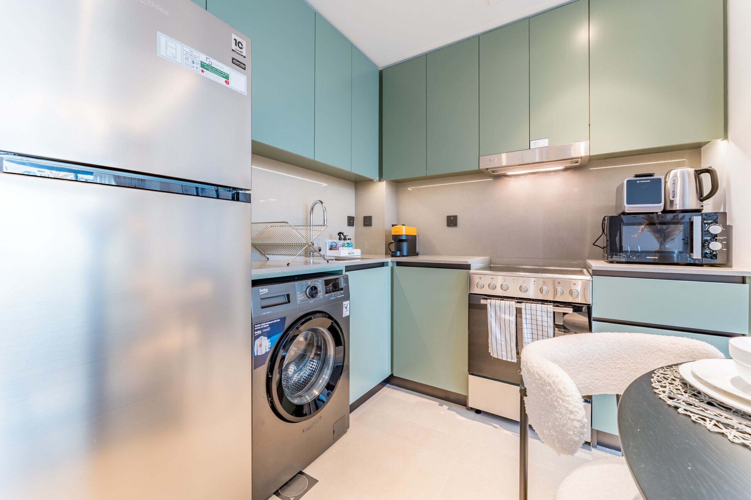 Une cuisine compacte équipée d’un lave-linge, d’une cuisinière et d’un four à micro-ondes.