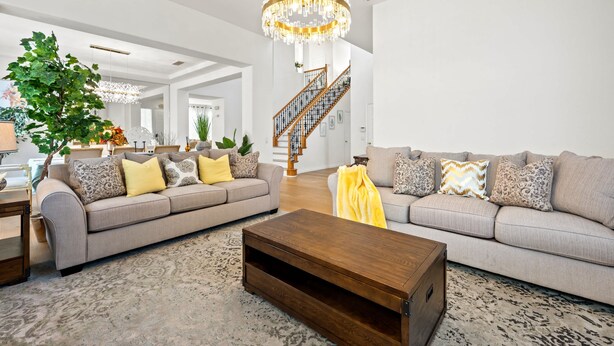 Un salon spacieux comprenant deux canapés, une table basse et un escalier menant à l’étage supérieur.