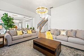 Ein geräumiges Wohnzimmer mit zwei Sofas, einem Couchtisch und einer Treppe, die zu einer oberen Etage führt.