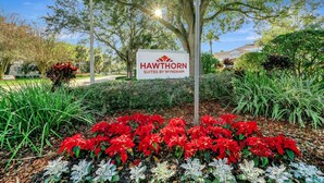 Schild für Hawthorn Suites by Wyndham, umgeben von einem Garten mit roten Weihnachtssternen und verschiedenen Pflanzen.