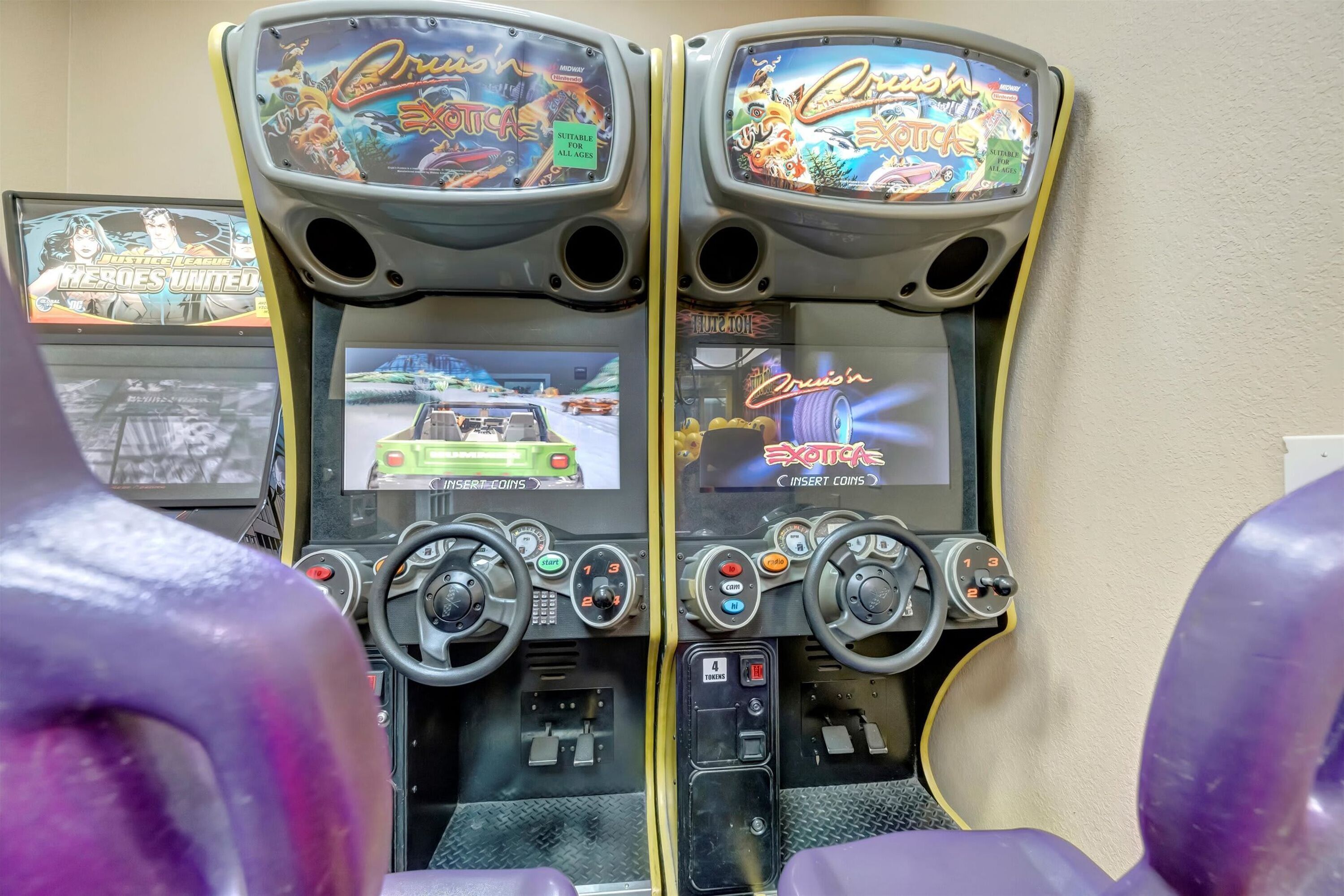 Two arcade gaming machines with steering wheels and multiple control buttons.
