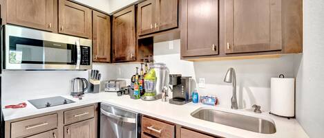 A modern kitchen with wooden cabinets, stainless steel appliances, and a built-in dishwasher.