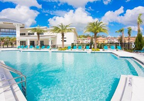 A swimming pool with lounge chairs and palm trees, surrounded by buildings. - Upstay Mansion w Cinema Games Pool- Sleeps 26 (Kissimmee)