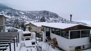 A snow-covered residential area with a modern house featuring large windows and a sloped roof. - Goura Guesthouse Garden Double Room Lake Doxa (Sikyona)